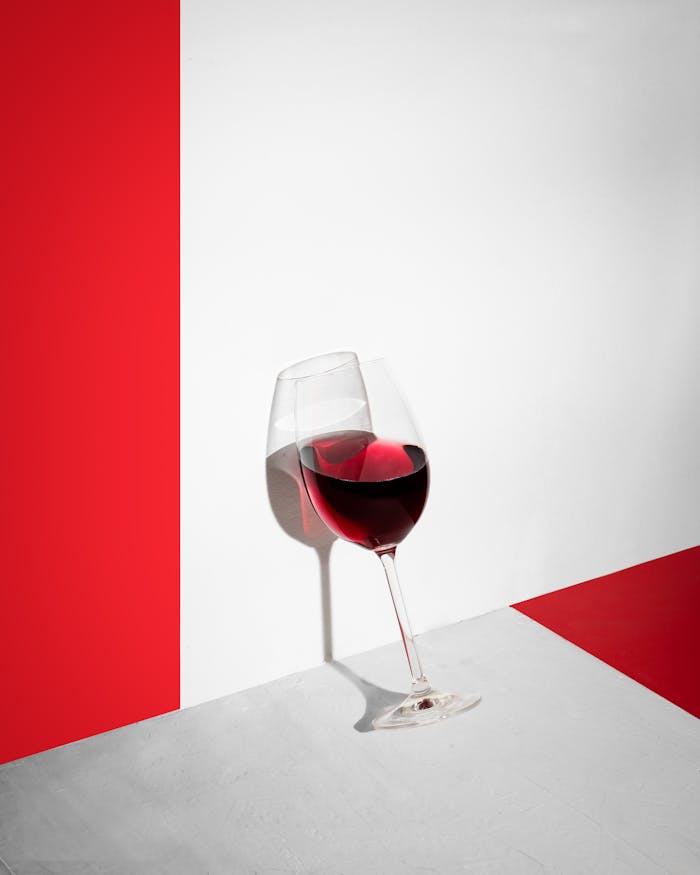 Captivating still life of a red wine glass against a striking red and white backdrop.