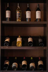 A diverse collection of red and white wine bottles arranged on a shelf in a wine bar.
